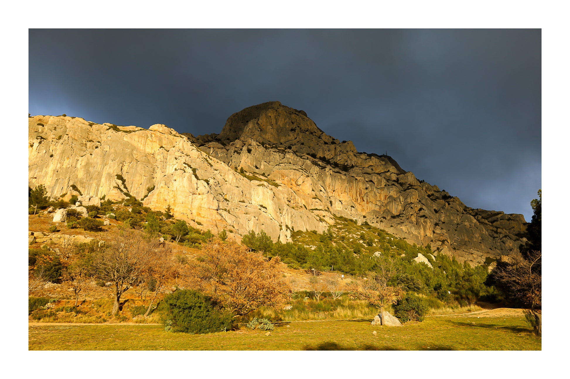 Falaise de la Sainte-Victoire dorée par le soleil avec gros nuages noirs au-dessus avec bordure