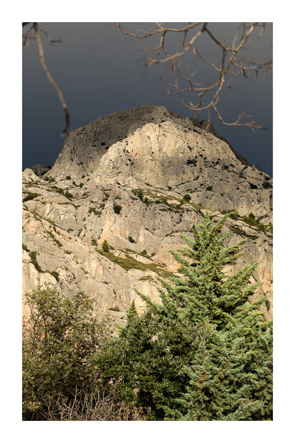 Sommet de la Sainte-Victoire encadré de branches, éclairé sur fond de ciel noir avec bordure