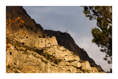 Croix au sommet de la Sainte-Victoire se détachant sur un ciel sombre avec bordure