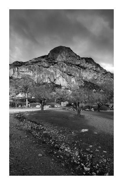 Amandiers au pied de la Sainte-Victoire illuminée par un ciel orageux bleu profond, noir et blanc avec bordure