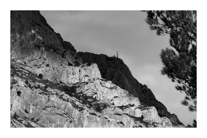Croix au sommet de la Sainte-Victoire se détachant sur un ciel sombre, noir et blanc avec bordure