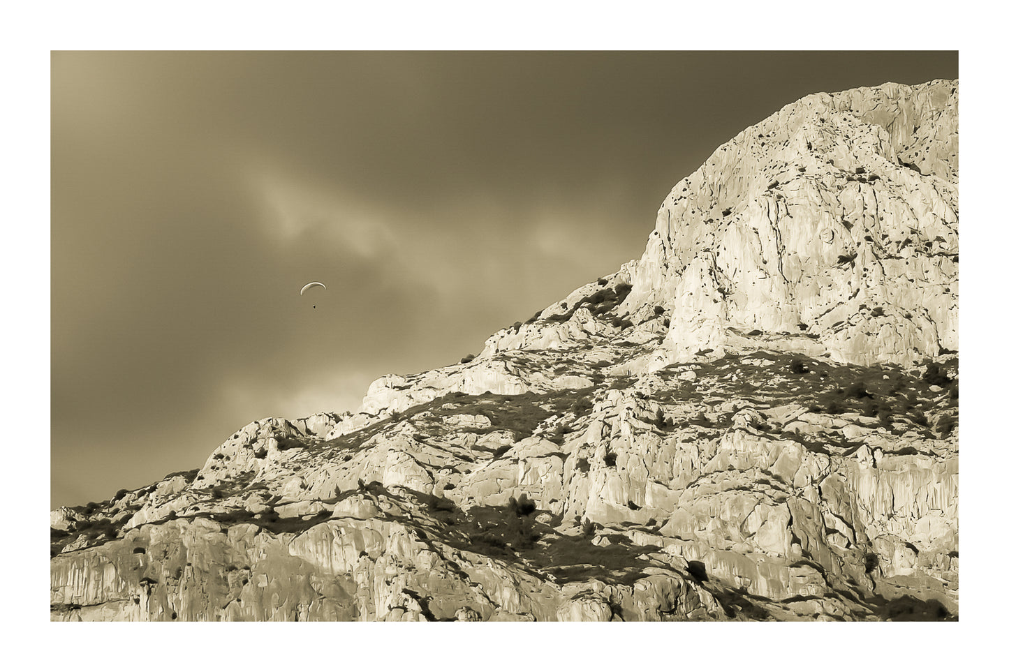 Parapente dans le ciel sombre au-dessus des falaises claires de la Sainte-Victoire, vintage avec bordure