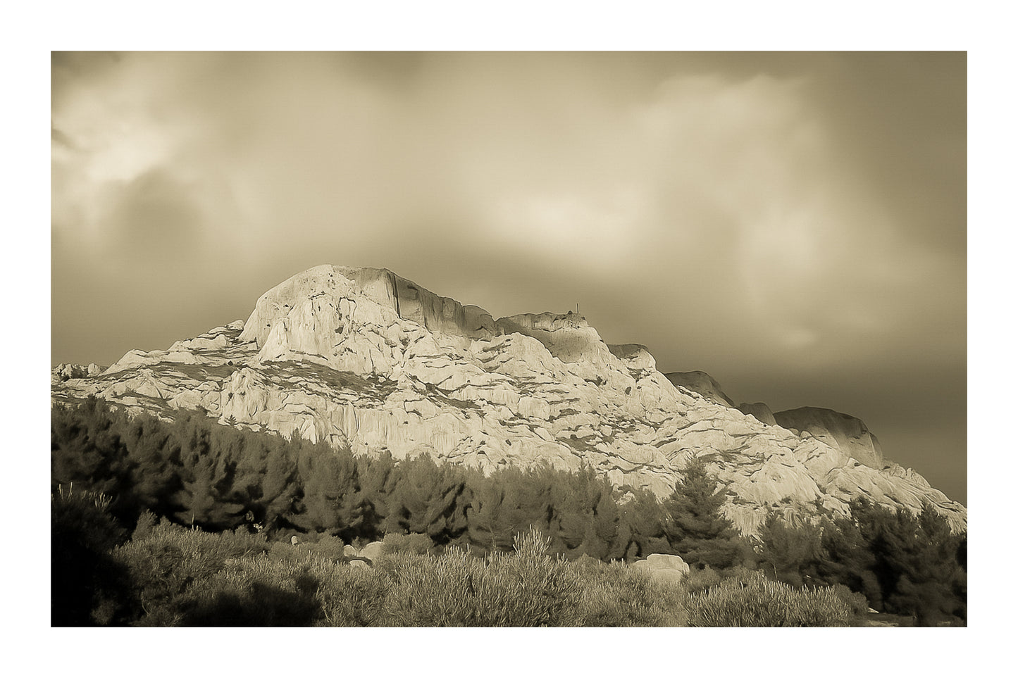 Crête de la Sainte-Victoire baignée de lumière dorée sous un ciel de nuages violets, vintage avec bordure