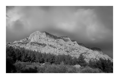 Crête de la Sainte-Victoire baignée de lumière dorée sous un ciel de nuages violets, noir et blanc avec bordure