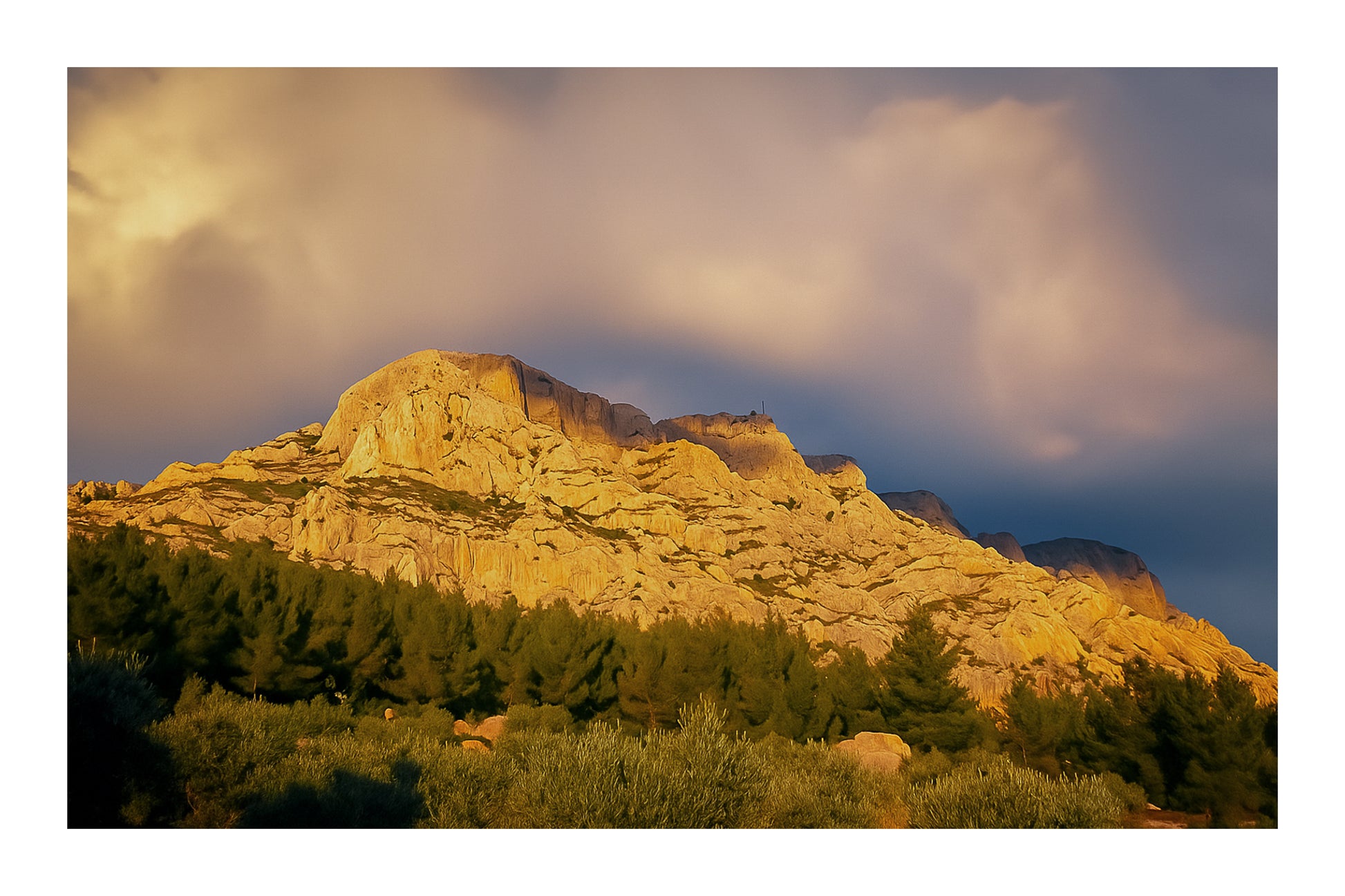 Crête de la Sainte-Victoire baignée de lumière dorée sous un ciel de nuages violets avec bordure