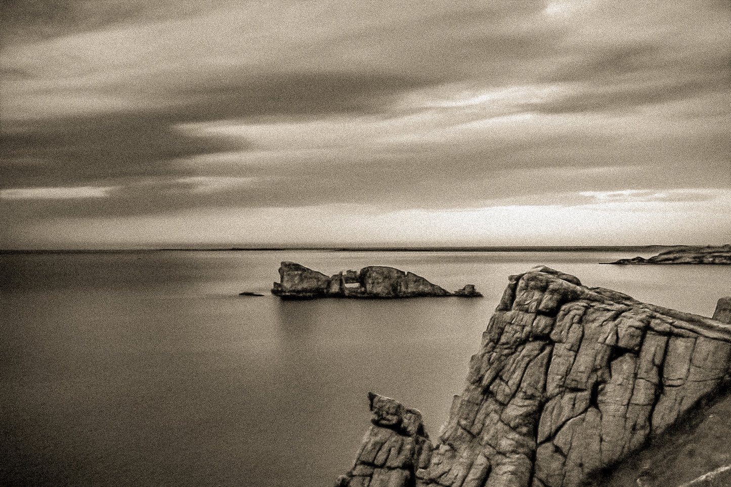 Îlot rocheux percé d’une arche au large de Pen Hir, ciel orageux et mer calme, vintage