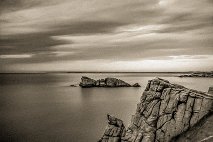 Îlot rocheux percé d’une arche au large de Pen Hir, ciel orageux et mer calme, vintage