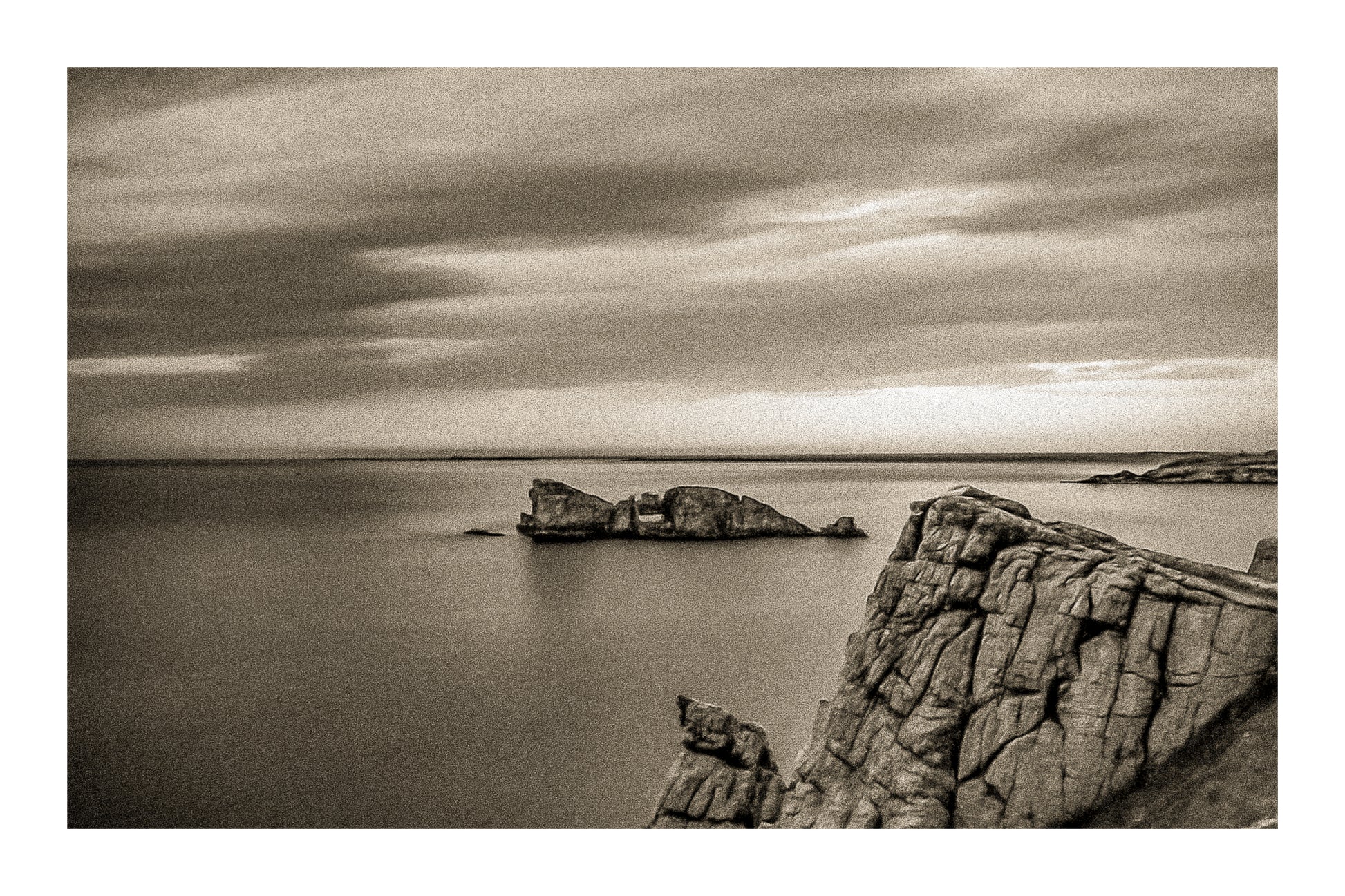 Îlot rocheux percé d’une arche au large de Pen Hir, ciel orageux et mer calme, vintage avec bordure