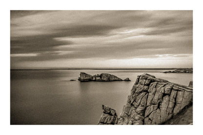 Îlot rocheux percé d’une arche au large de Pen Hir, ciel orageux et mer calme, vintage avec bordure
