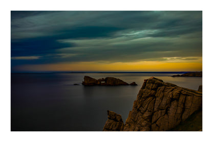 Îlot rocheux percé d’une arche au large de Pen Hir, ciel orageux et mer calme avec bordure