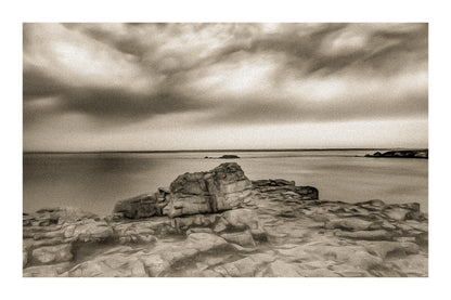 Rocher au premier plan sous un ciel d’orage coloré au cap de Pen Hir en Bretagne, vintage avec bordure