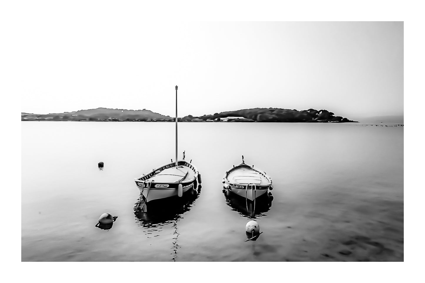 Deux barques côte à côte sur eau calme, îles au loin, douceur de soirée au Brusc, noir et blanc avec bordure