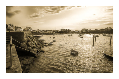 Vue du port de Portsall au coucher du soleil, muret de pierre et rochers au premier plan, petites barques au mouillage sur mer dorée, vintage avec bordure