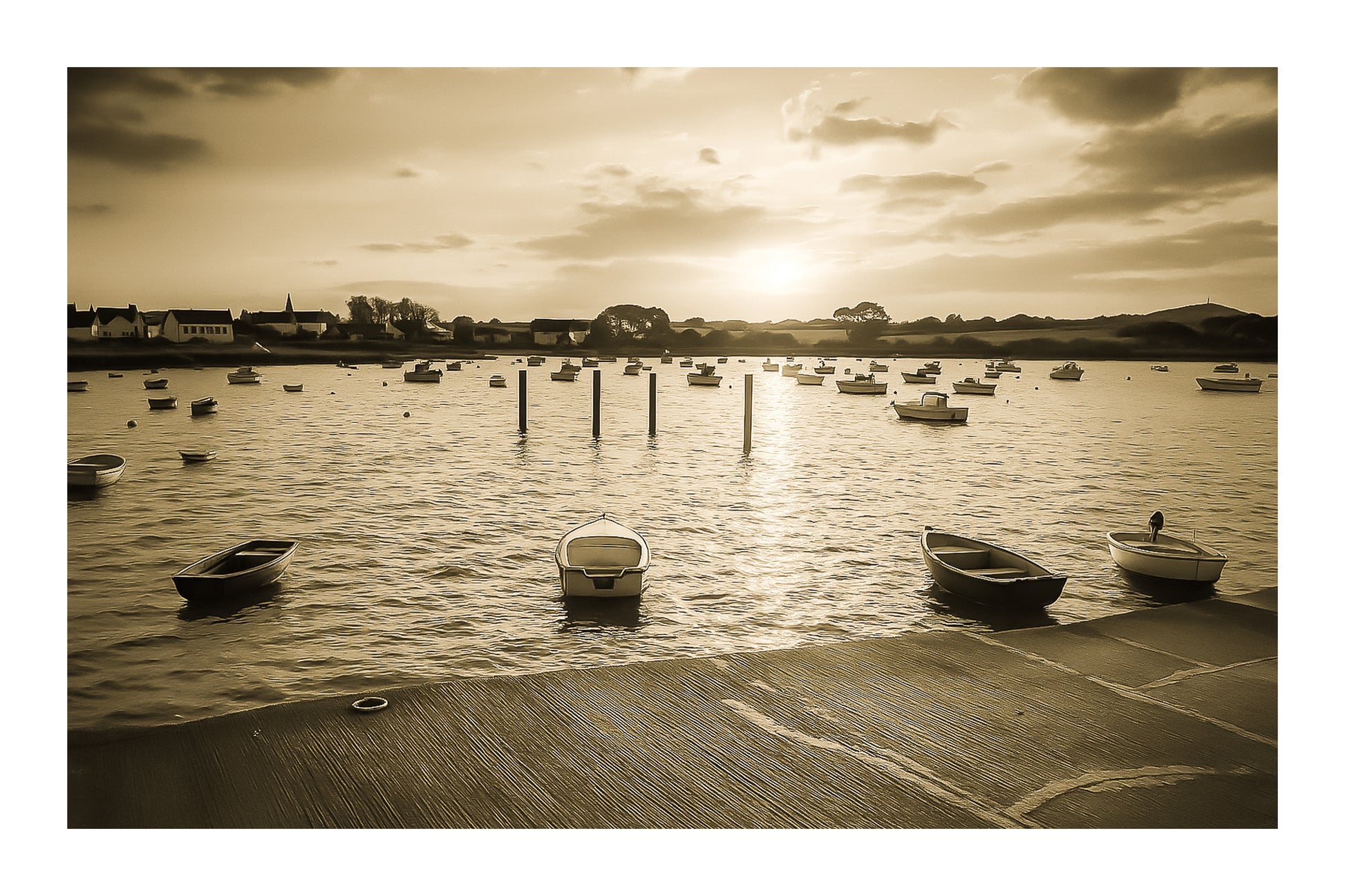 Petites embarcations alignées à Portsall, soleil rasant et rangées de bouées, reflets chauds sur l’eau tranquille, vintage avec bordure