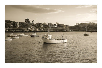 Petit bateau de pêche au premier plan devant les maisons et rochers de Portsall, ciel clair et tonalités chaudes du soir, vintage avec bordure