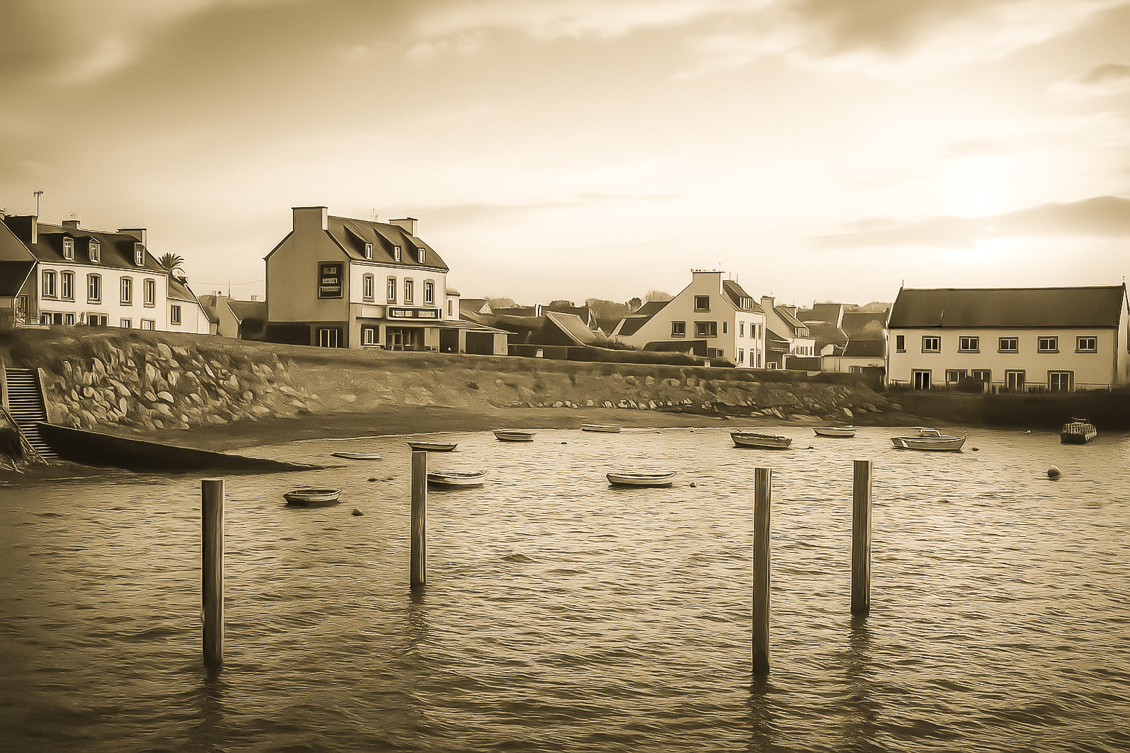 Maisons du bord de mer à Portsall baignées de lumière dorée, poteaux d’amarrage et barques dispersées sur l’anse, vintage