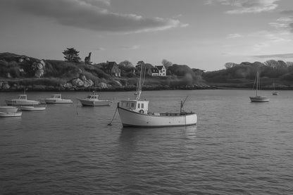 Petit bateau de pêche au premier plan devant les maisons et rochers de Portsall, ciel clair et tonalités chaudes du soir, noir et blanc