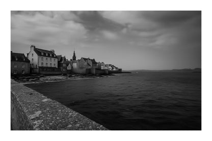 Panorama de Roscoff longeant la digue, maisons serrées au bord de l’eau face à la mer d’Iroise, noir et blanc avec bordure