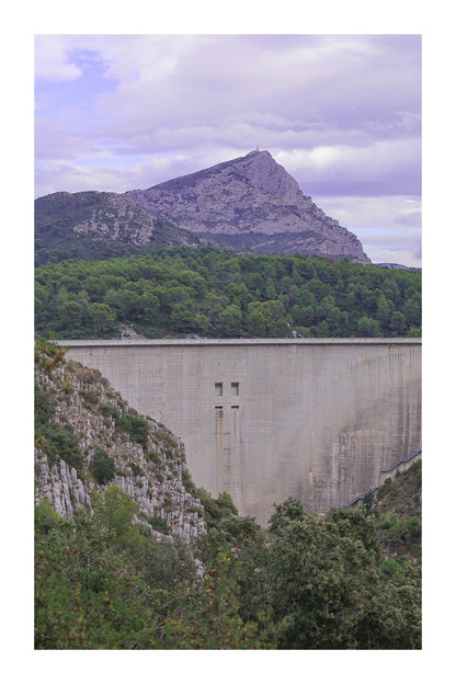 Barrage massif au premier plan avec la Sainte-Victoire en arrière-plan, forêt méditerranéenne et ciel nuageux avec bordure