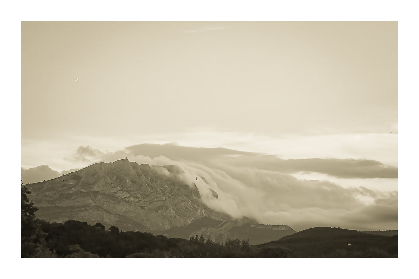Sainte-Victoire au crépuscule avec nuages en cascade sur les crêtes, avant-plans sombres de collines et d’arbres, vintage avec bordure