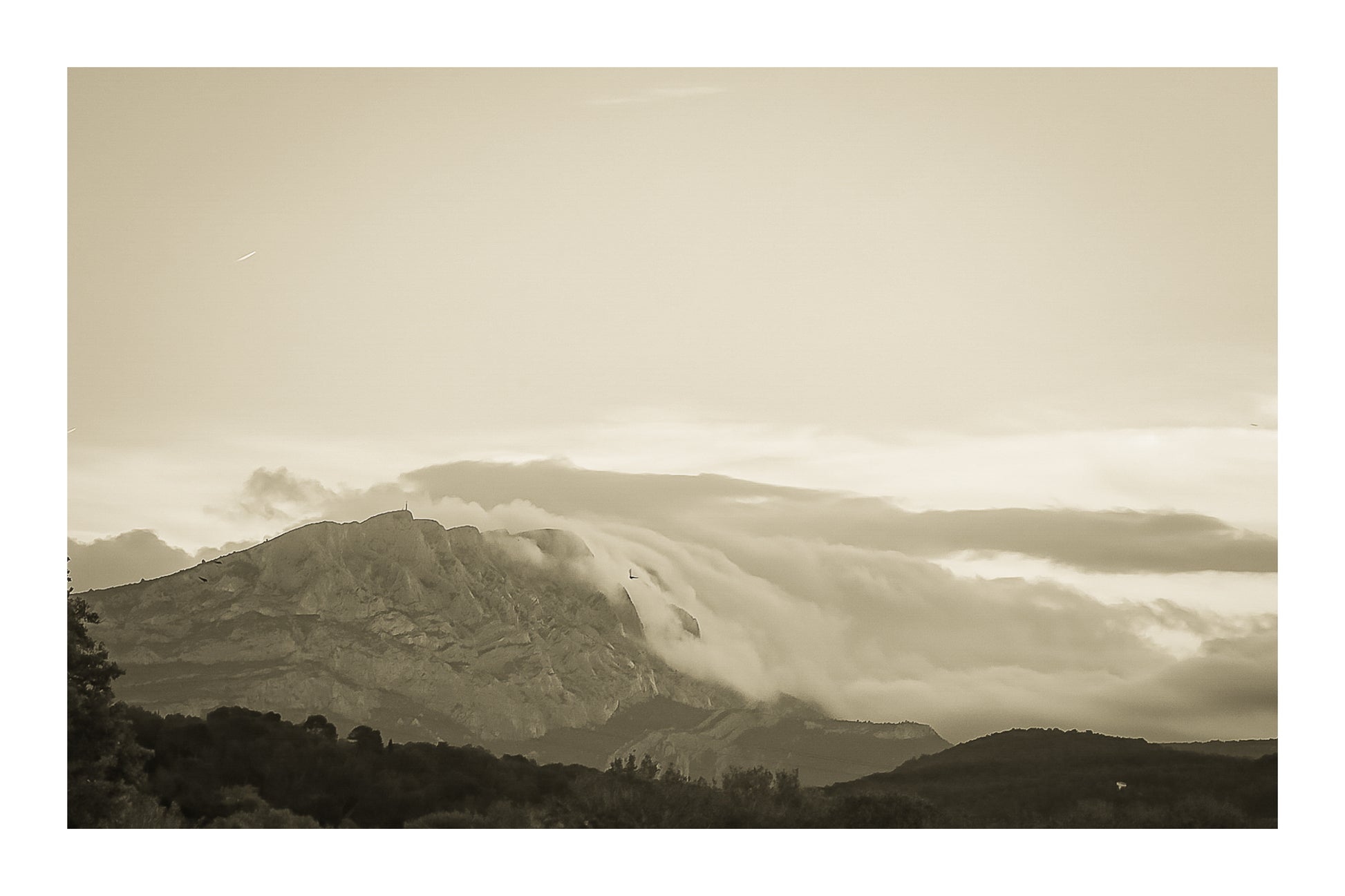 Sainte-Victoire au crépuscule avec nuages en cascade sur les crêtes, avant-plans sombres de collines et d’arbres, vintage avec bordure