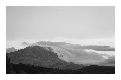Sainte-Victoire au crépuscule avec nuages en cascade sur les crêtes, avant-plans sombres de collines et d’arbres, noir et blanc avec bordure