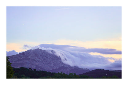 Sainte-Victoire au crépuscule avec nuages en cascade sur les crêtes, avant-plans sombres de collines et d’arbres avec bordure