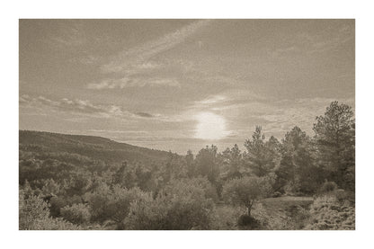 Chemin de garrigue au crépuscule, soleil bas dans un ciel orangé éclairant les buissons et les collines lointaines, vintage avec bordure