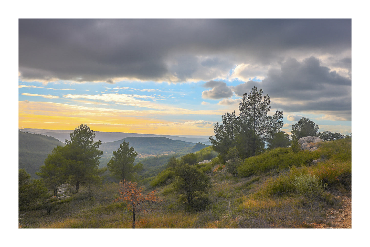 Paysage de garrigue au lever du jour sous de gros nuages, vue sur les collines de la Sainte-Victoire avec bordure