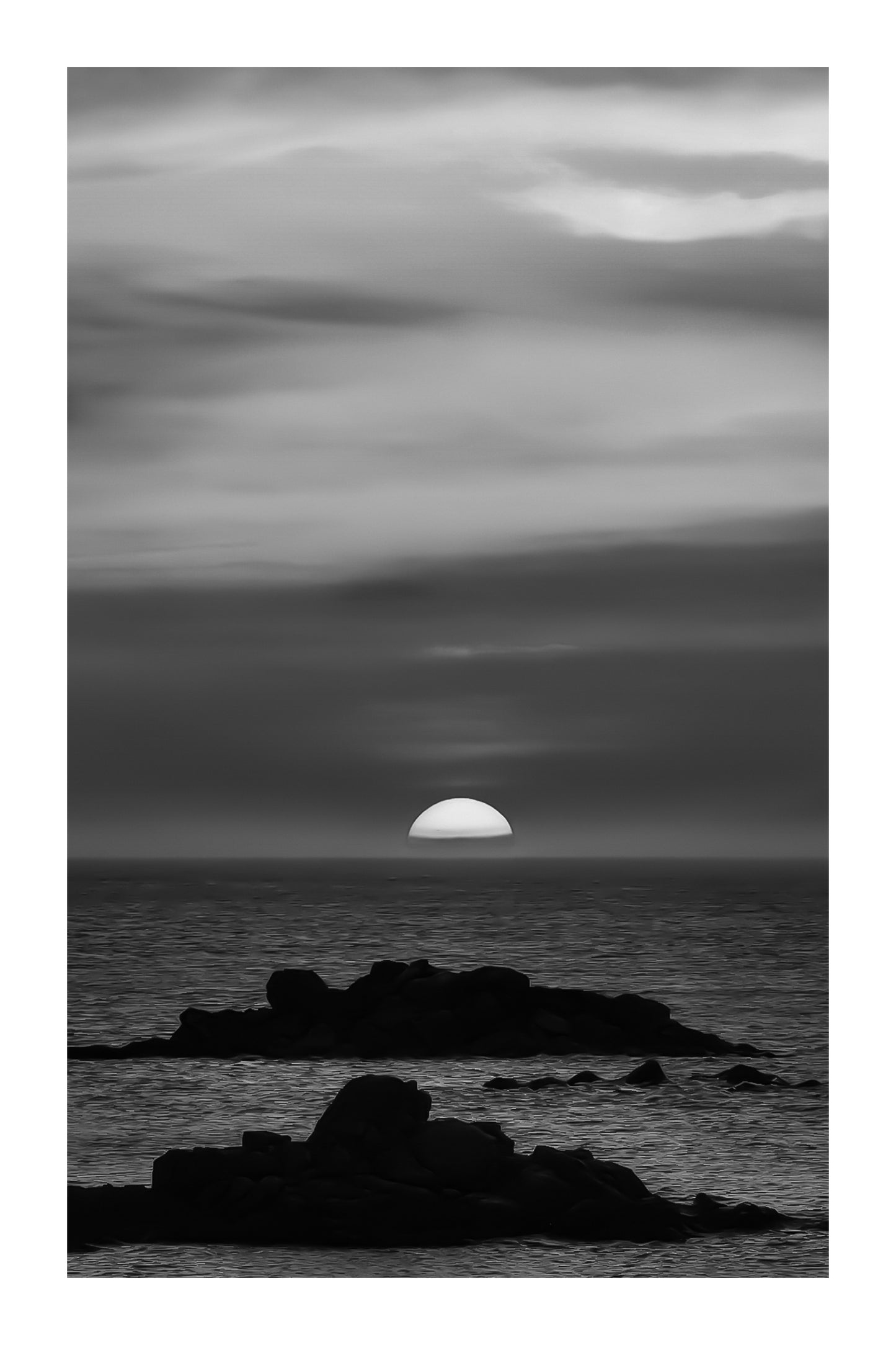 Coucher de soleil pastel avec ciel rose, jaune et bleu au-dessus de l’océan et d’îlots rocheux à l’Aber Wrac’h, noir et blanc avec bordure