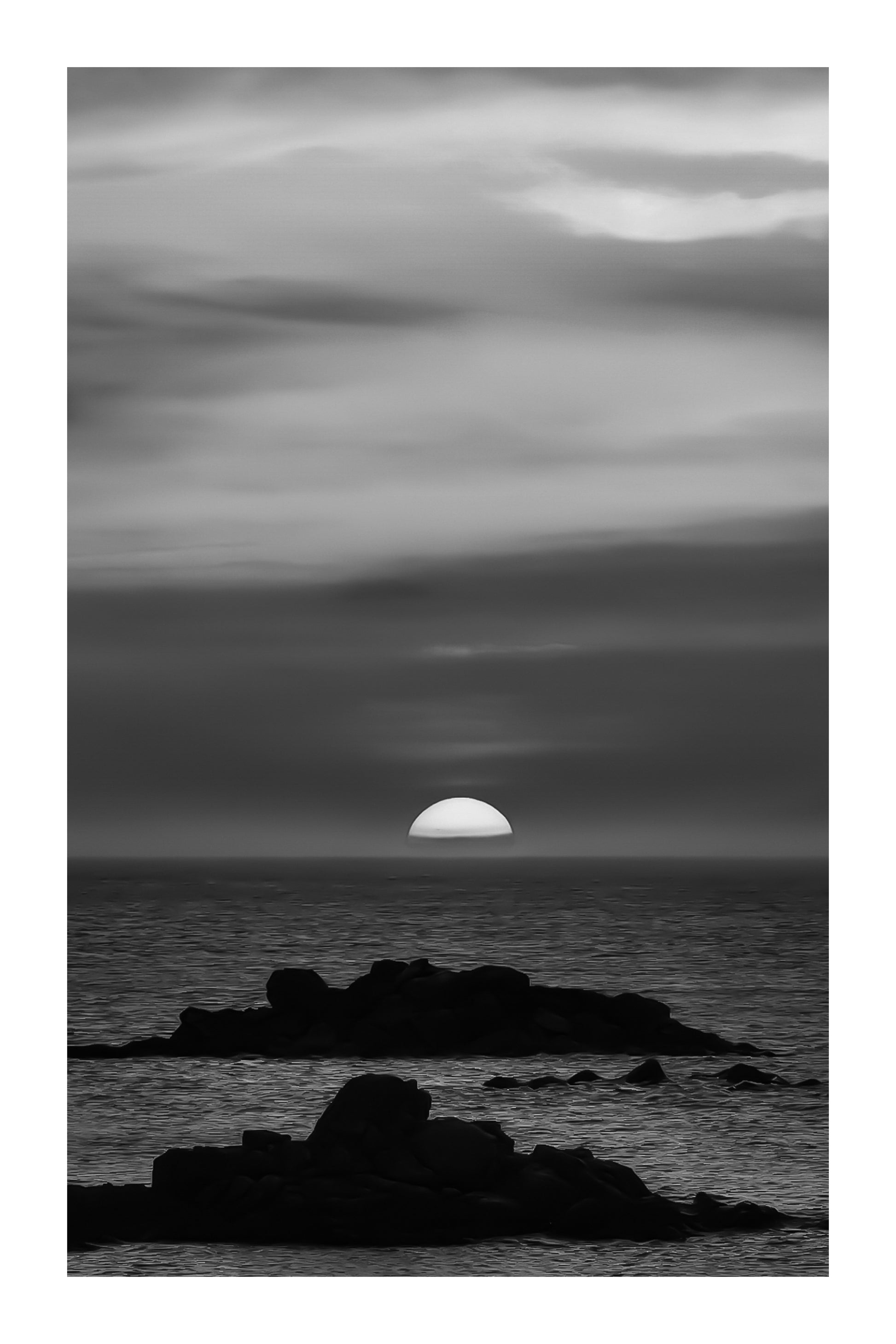 Coucher de soleil pastel avec ciel rose, jaune et bleu au-dessus de l’océan et d’îlots rocheux à l’Aber Wrac’h, noir et blanc avec bordure