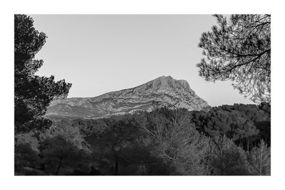 Panorama de la montagne Sainte-Victoire et de la forêt de pins sous une lumière chaude de fin de journée, noir et blanc avec bordure