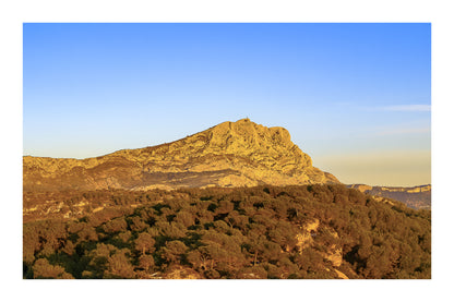 Crête de la Sainte-Victoire entièrement dorée par le soleil au-dessus d’une mer de pins avec bordure