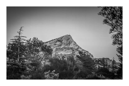 Montagne Sainte-Victoire illuminée par le soleil couchant derrière une forêt de pins en Provence, version noir et blanc avec bordure