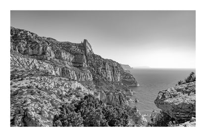 Falaises monumentales des calanques de Sugiton plongeant vers la Méditerranée par ciel bleu profond, noir et blanc avec bordure