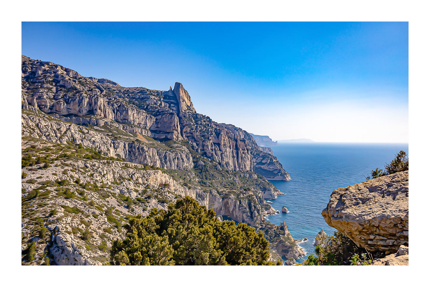 Falaises monumentales des calanques de Sugiton plongeant vers la Méditerranée par ciel bleu profond avec bordure