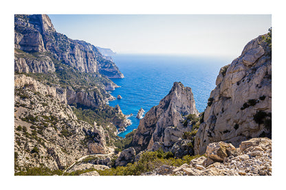 Vue plongeante entre deux parois rocheuses sur l’eau turquoise de la calanque de Sugiton avec bordure