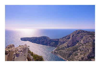 Éperon rocheux avançant dans la mer scintillante au large des calanques de Marseille avec bordure