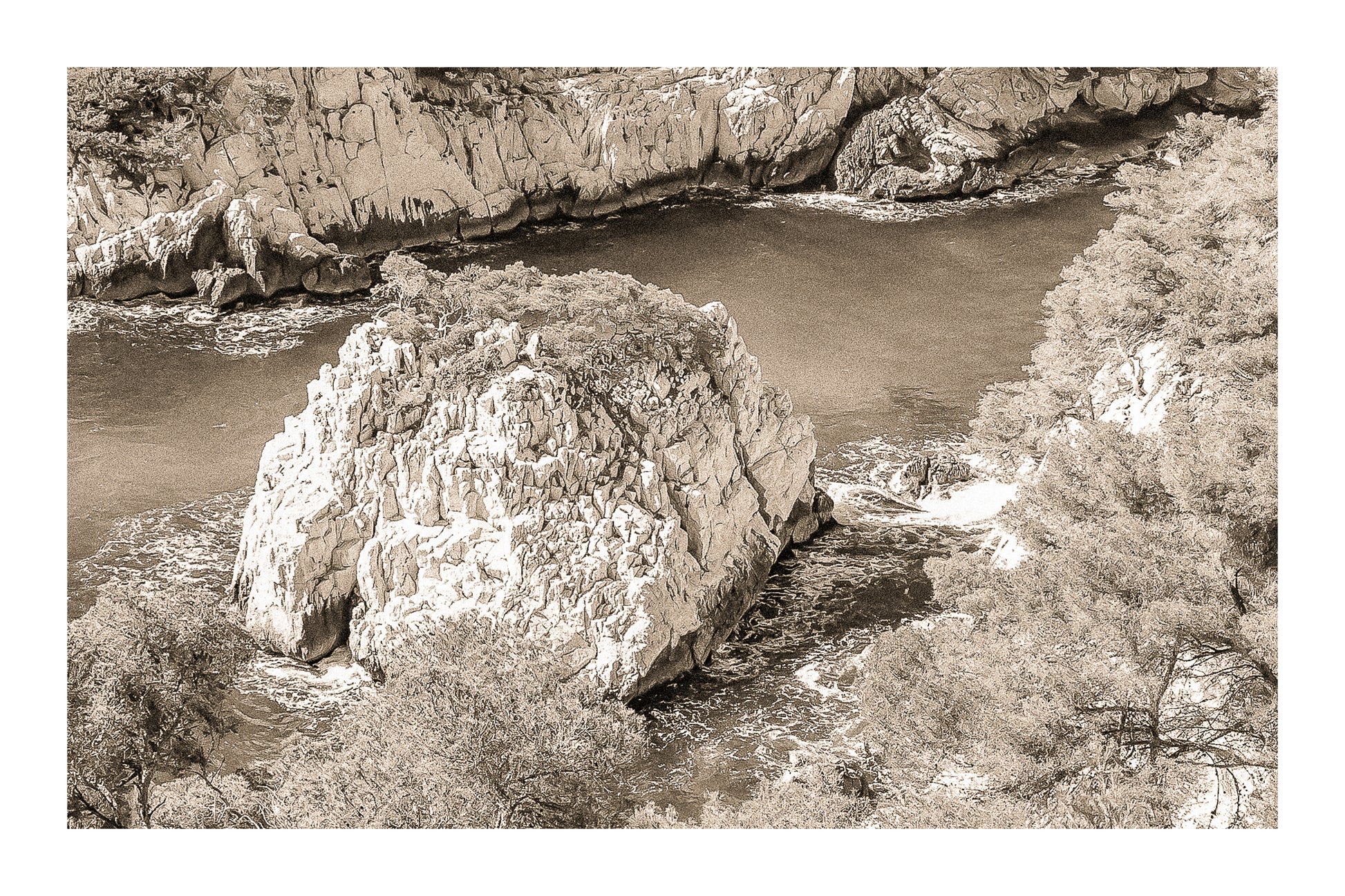 Petit îlot rocheux couvert de pins au centre d’une anse turquoise dans les calanques, vintage avec bordure