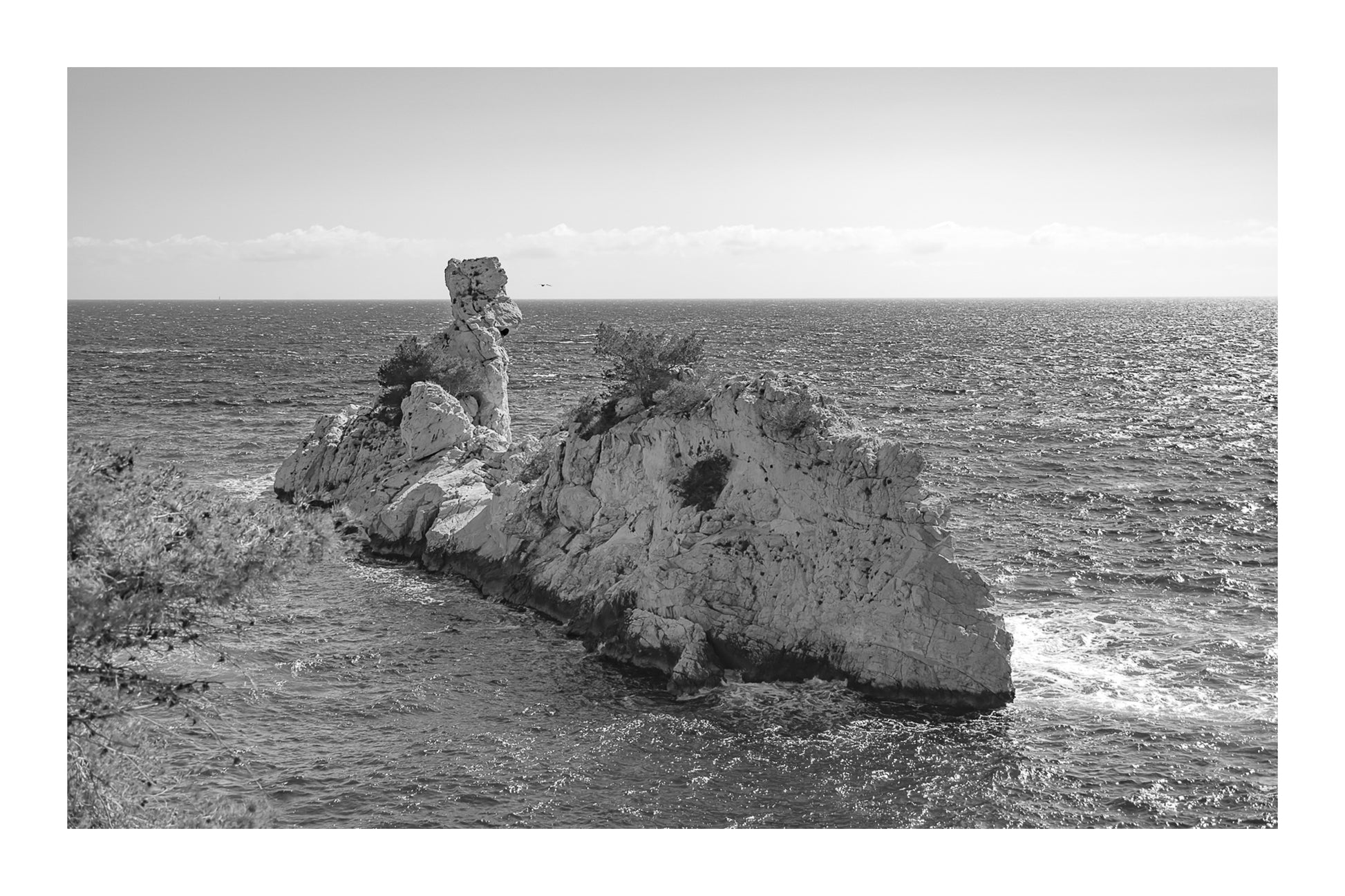 Rocher du Torpilleur battu par le mistral à l’entrée de la calanque de Sugiton, noir et blanc avec bordure