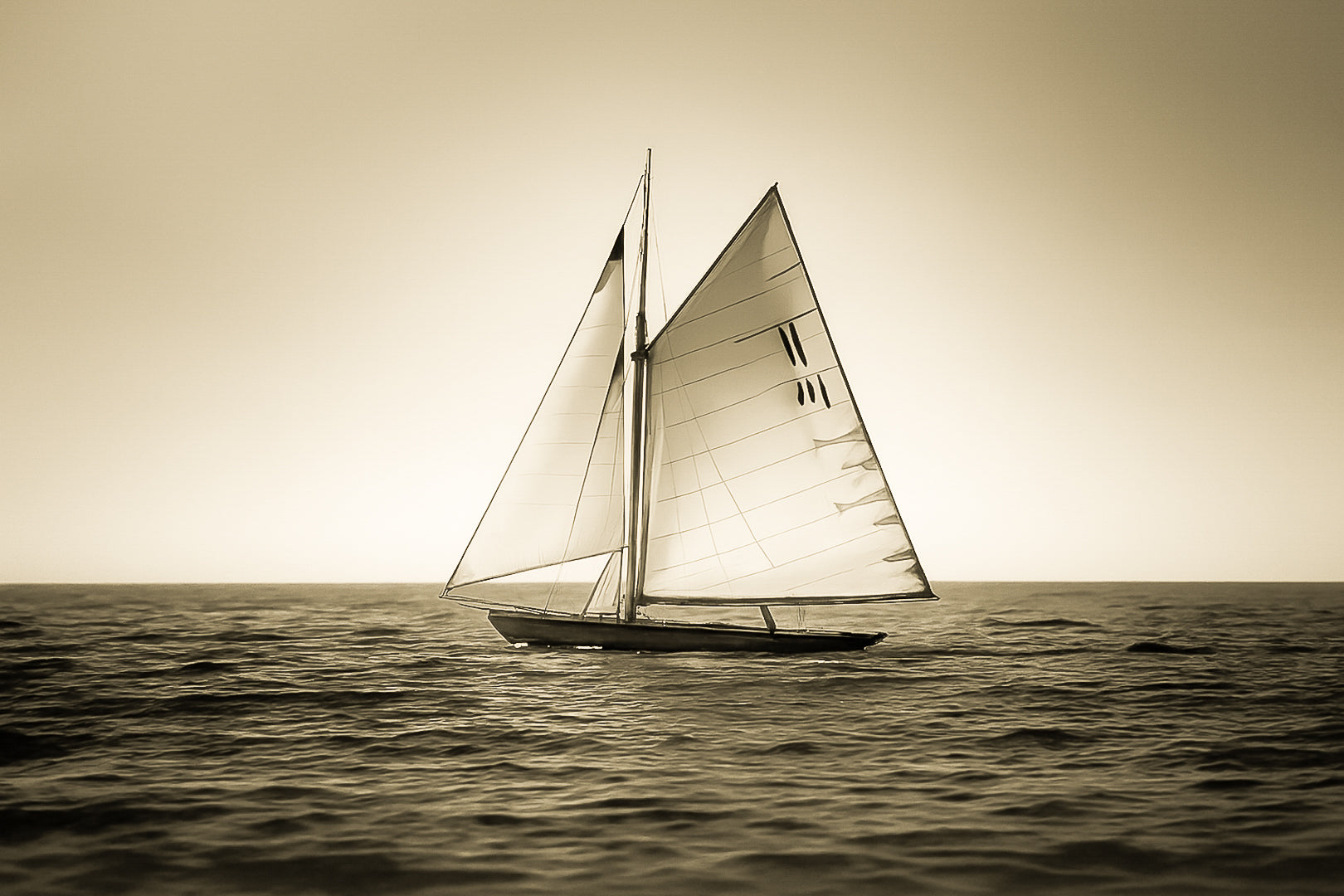 Voilier classique en navigation au coucher du soleil sur une mer calme en Méditerranée, voiles dorées par la lumière, vintage