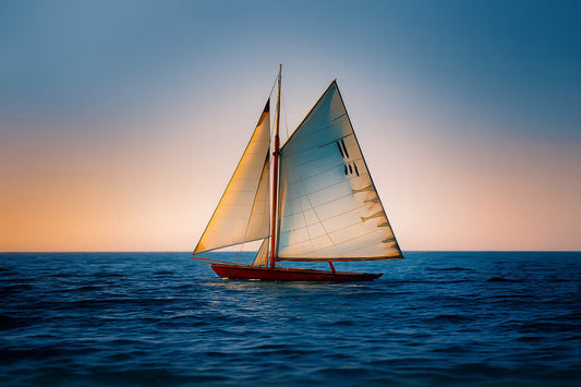 Voilier classique en navigation au coucher du soleil sur une mer calme en Méditerranée, voiles dorées par la lumière