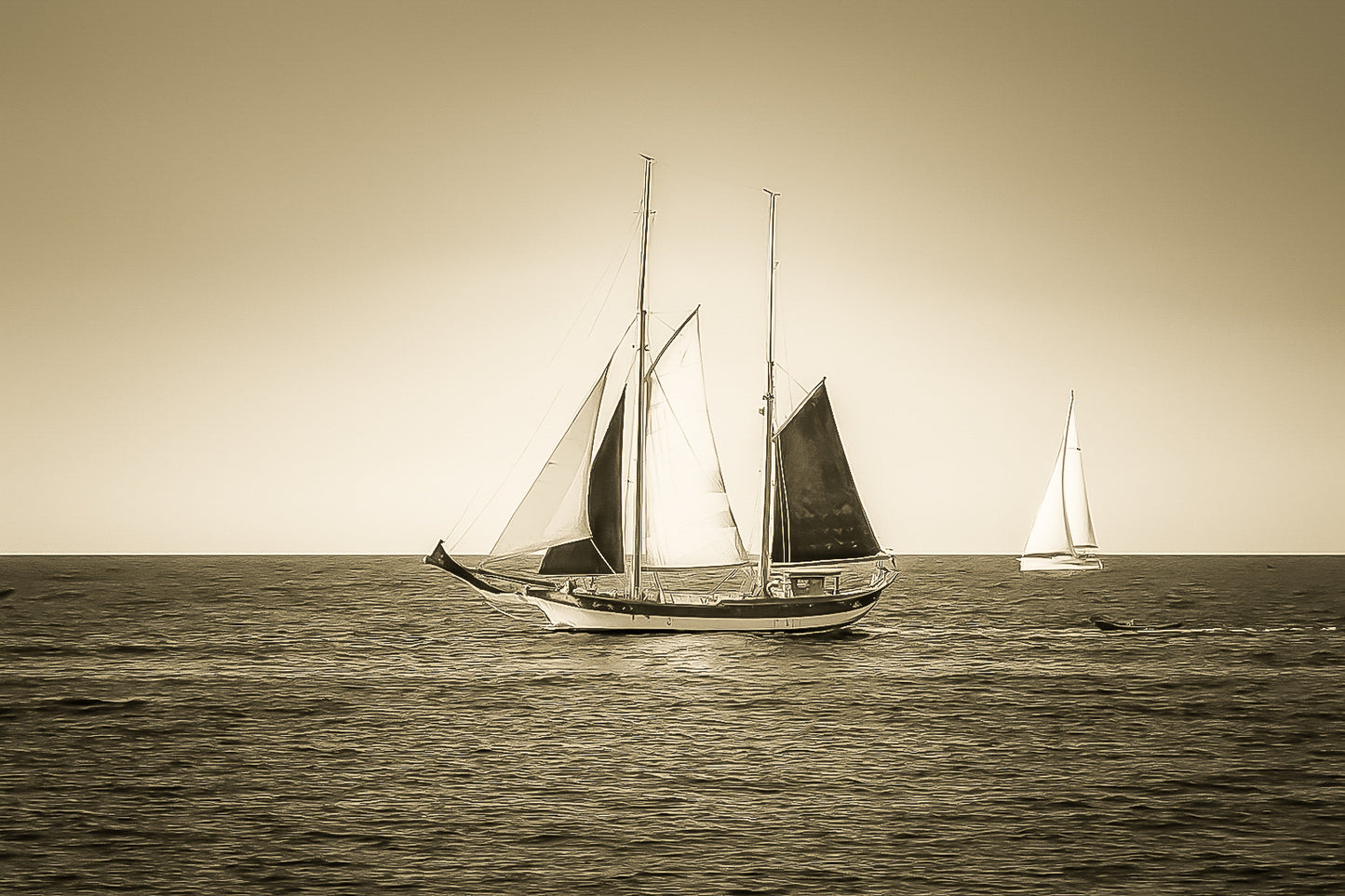 Deux voiliers traditionnels naviguant au large au crépuscule, ciel dégradé et reflets chauds sur la Méditerranée, vintage