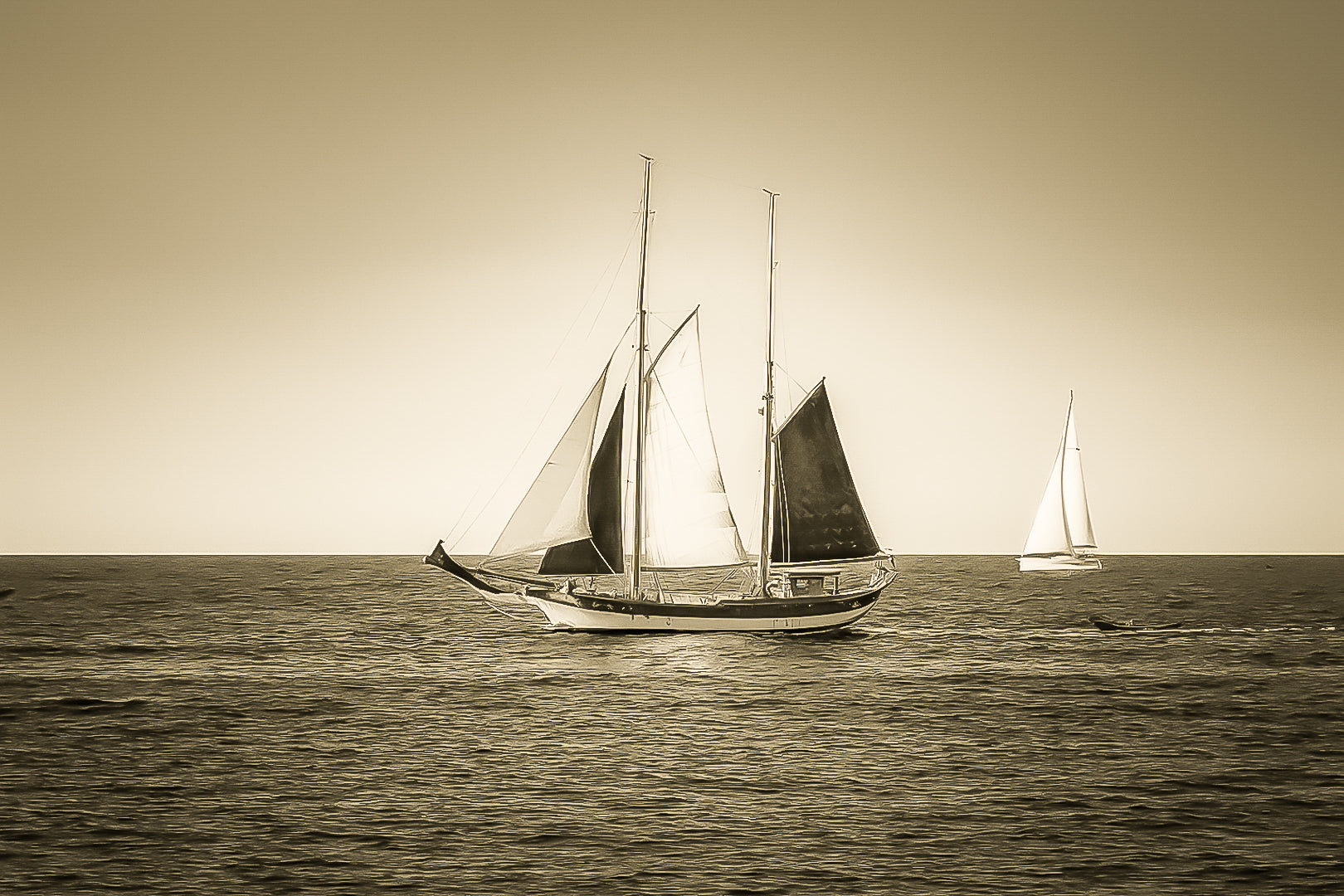Deux voiliers traditionnels naviguant au large au crépuscule, ciel dégradé et reflets chauds sur la Méditerranée, vintage