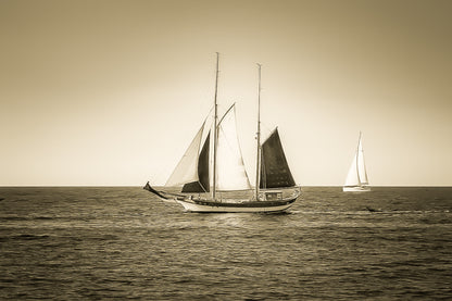 Deux voiliers traditionnels naviguant au large au crépuscule, ciel dégradé et reflets chauds sur la Méditerranée, vintage