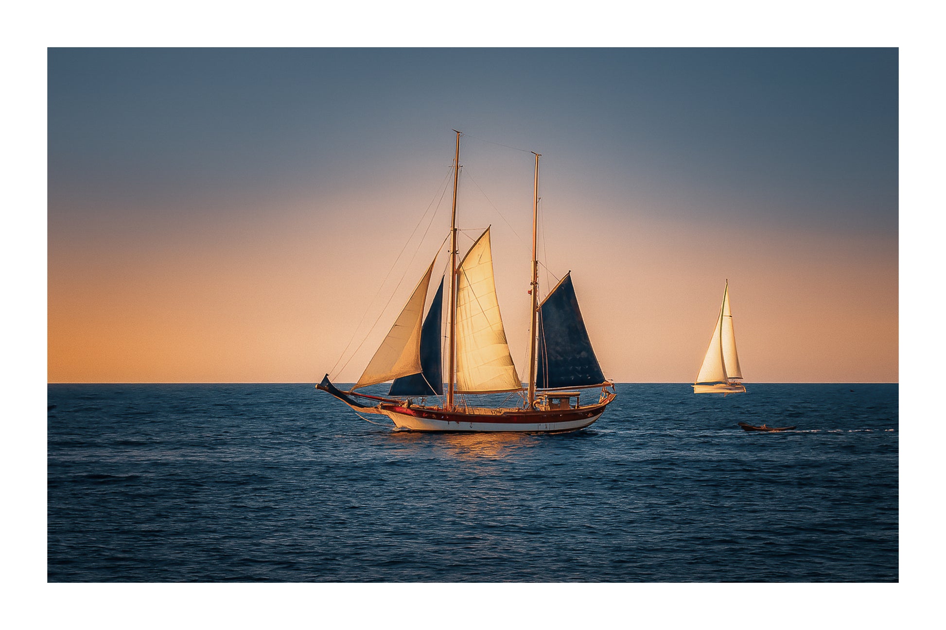 Deux voiliers traditionnels naviguant au large au crépuscule, ciel dégradé et reflets chauds sur la Méditerranée avec bordure